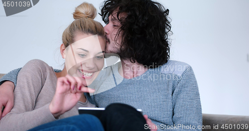 Image of couple relaxing at  home with tablet computers