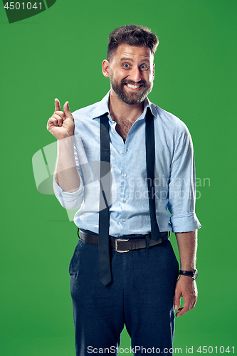 Image of The young attractive man looking suprised isolated on green