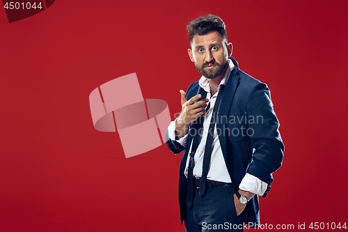 Image of Suspiciont. Doubtful pensive man with thoughtful expression making choice against red background