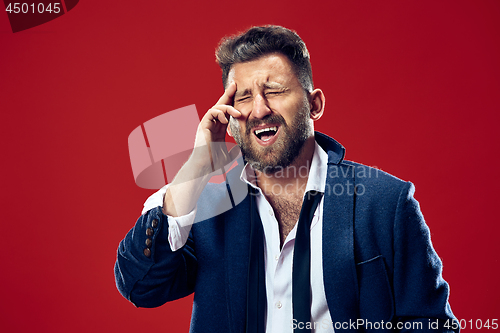 Image of Man having headache. Isolated over red background.