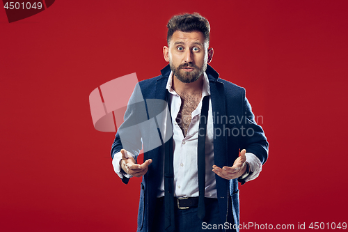 Image of The young attractive man looking suprised isolated on red