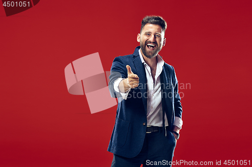 Image of The happy business man point you and want you, half length closeup portrait on red background.