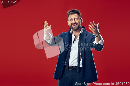 Image of The happy business man standing and smiling against red background.