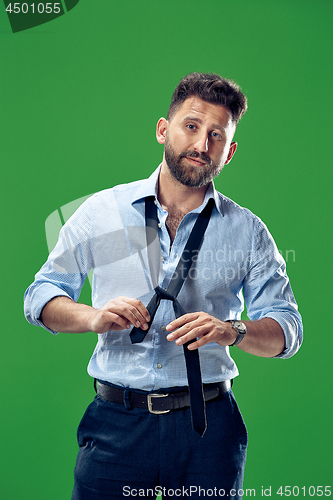 Image of Businessman tying his tie at green studio