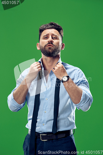Image of Male beauty concept. Portrait of a fashionable young man with stylish haircut wearing trendy suit posing over green background.