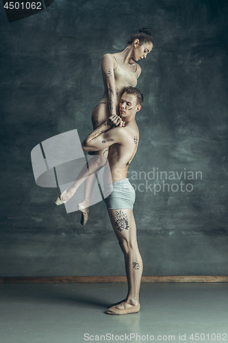 Image of The young modern ballet dancers posing on gray studio background