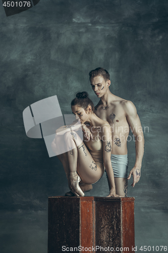 Image of The young modern ballet dancers posing on gray studio background