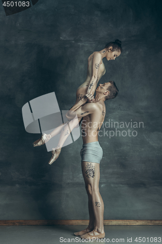 Image of The young modern ballet dancers posing on gray studio background