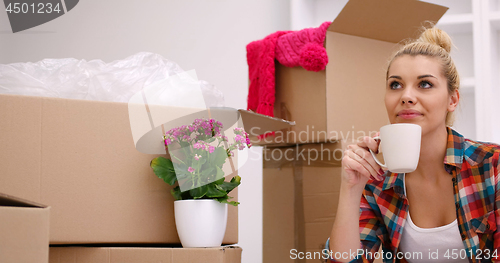 Image of woman with many cardboard boxes sitting on floor