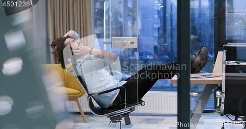 Image of businessman sitting with legs on desk