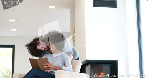 Image of multiethnic couple hugging in front of fireplace