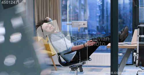 Image of businessman sitting with legs on desk