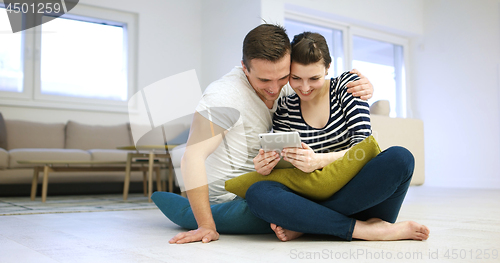 Image of Young Couple using digital tablet on the floor