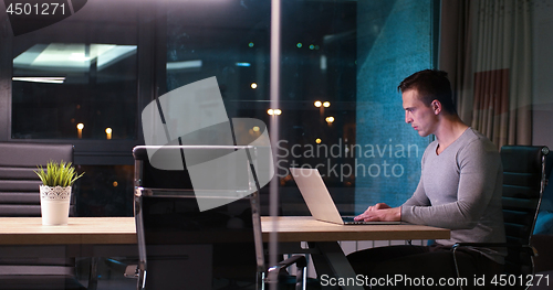 Image of man working on laptop in dark office