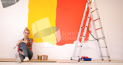Image of young female painter sitting on floor