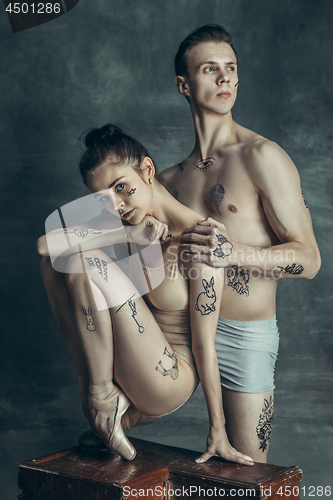 Image of The young modern ballet dancers posing on gray studio background