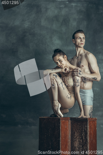 Image of The young modern ballet dancers posing on gray studio background