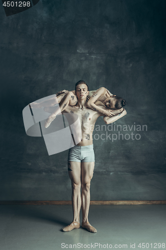 Image of The young modern ballet dancers posing on gray studio background