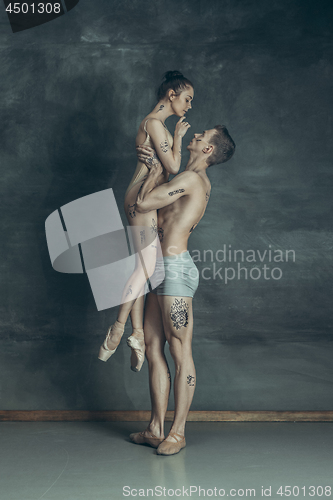 Image of The young modern ballet dancers posing on gray studio background