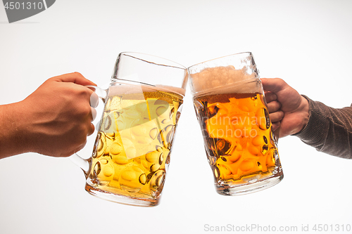 Image of hands with mugs of beer toasting creating splash isolated on white background