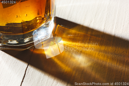 Image of Whiskey in glass, ice cub served in a short glass on white table