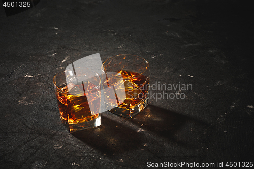 Image of Whiskey in glass, ice cub served in a short glass on black table