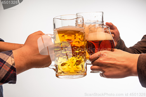 Image of hands with mugs of beer toasting creating splash isolated on white background