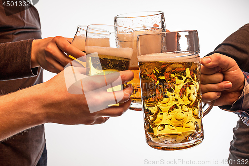 Image of hands with mugs of beer toasting creating splash isolated on white background