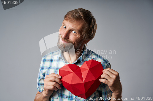 Image of Smiling mature man in checkered shirt holding heart shape