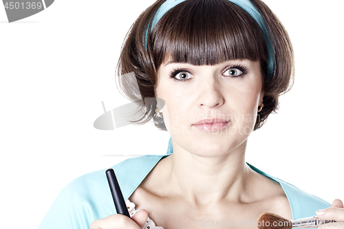 Image of Attractive brunet woman in blue dress with two make-up brushes