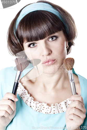 Image of Pretty woman in blue dress with two make-up brushes