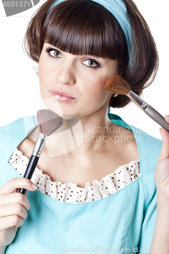 Image of Attractive brunet woman in blue dress with two make-up brushes