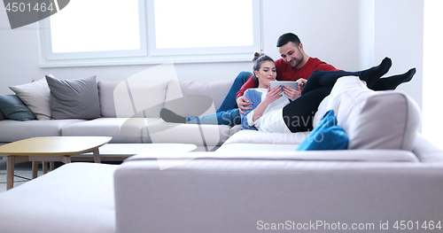 Image of couple relaxing at  home with tablet computers