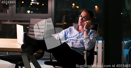Image of businessman sitting with legs on desk at office