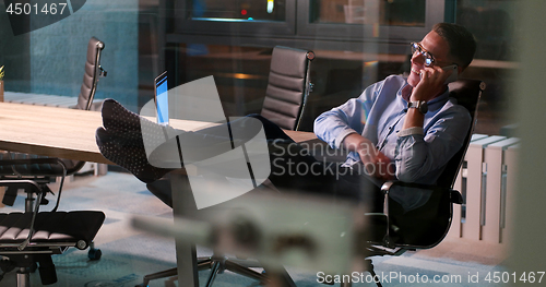Image of businessman sitting with legs on desk at office