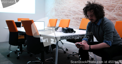 Image of man using mobile phone in dark office