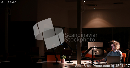 Image of man working on computer in dark office