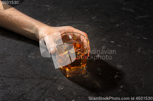 Image of Whiskey in glass, ice cub served in a short glass on black table