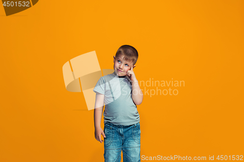 Image of The happy teen boy standing and smiling against orange background.
