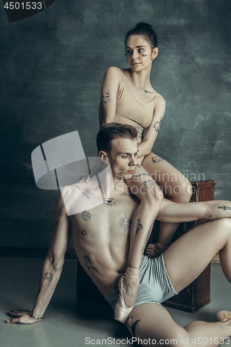 Image of The young modern ballet dancers posing on gray studio background