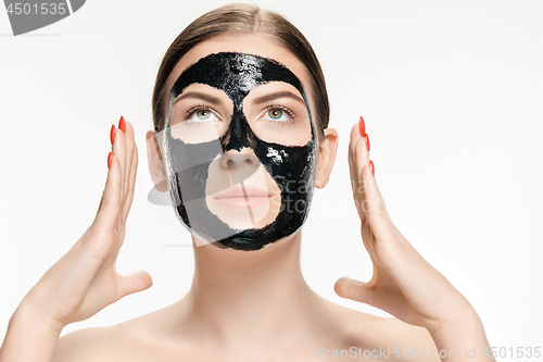 Image of Young beautiful woman applying a mask for the face of the therapeutic black mud. Spa treatment