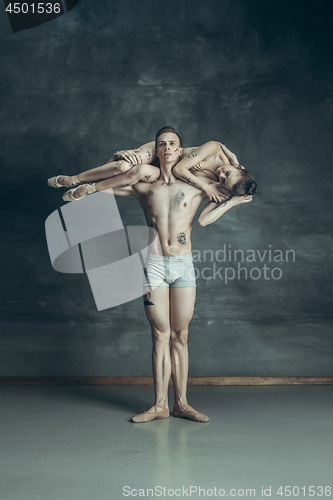 Image of The young modern ballet dancers posing on gray studio background