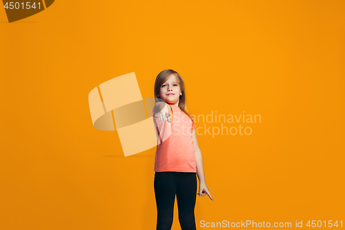 Image of The happy teen girl pointing to you, half length closeup portrait on orange background.