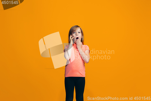 Image of The happy teen girl standing and smiling against orange background.