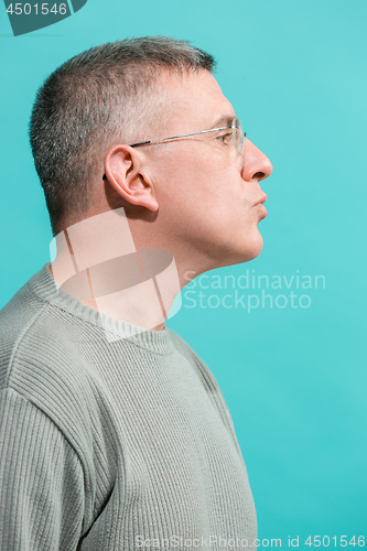Image of The serious businessman standing and looking at camera against blue background.
