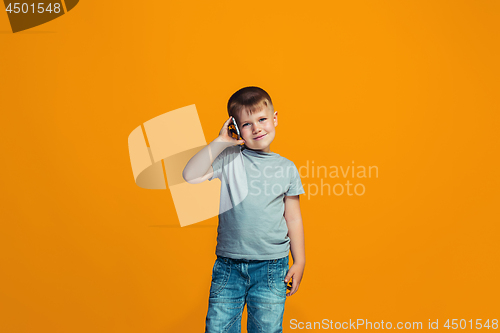 Image of The happy teen boy standing and smiling against orange background.