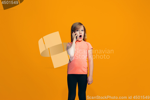 Image of The happy teen girl standing and smiling against orange background.