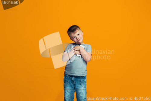 Image of The happy teen boy standing and smiling against orange background.