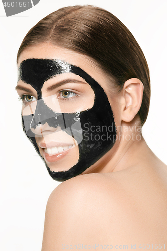 Image of Young beautiful woman applying a mask for the face of the therapeutic black mud. Spa treatment