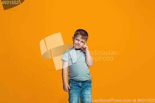 Image of The happy teen boy standing and smiling against orange background.